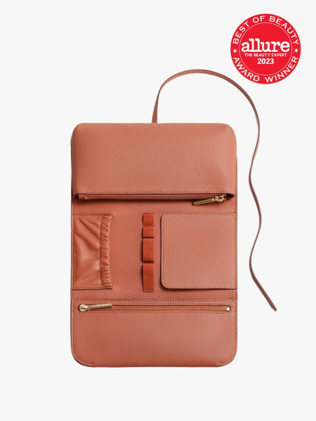 Cuyana Travel Beauty Roll in coral color on light grey background with red best of beauty seal