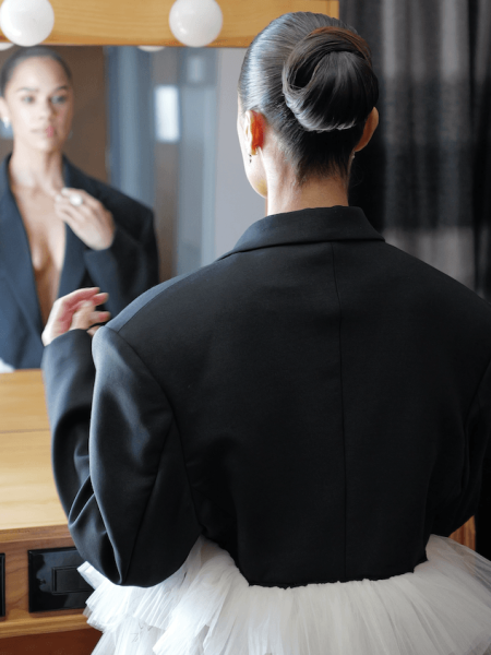 Ballerina Misty Copeland looking into a mirror with her hair in a ballet bun.